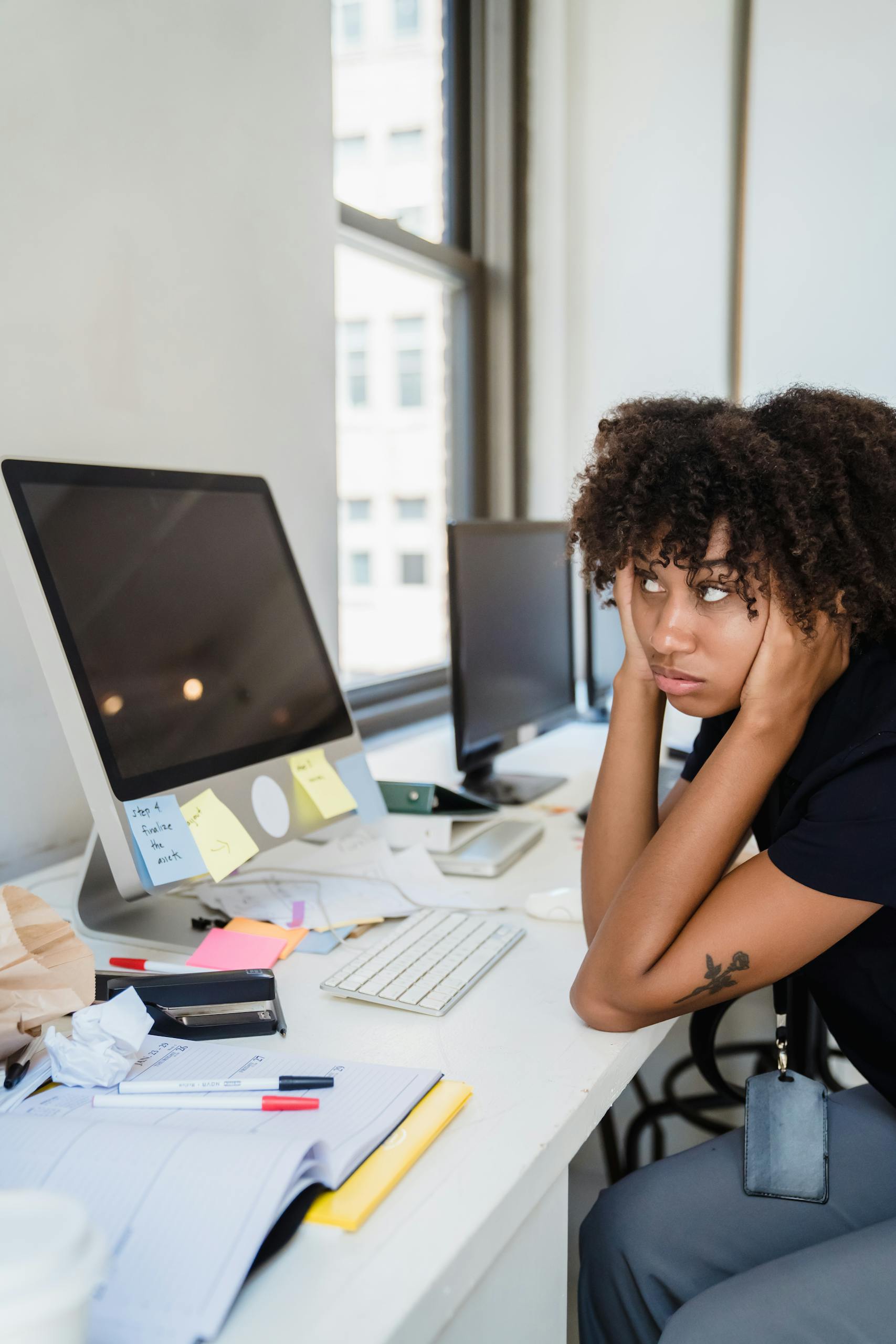 Focused and frustrated woman working in a modern office setting, appearing overworked.